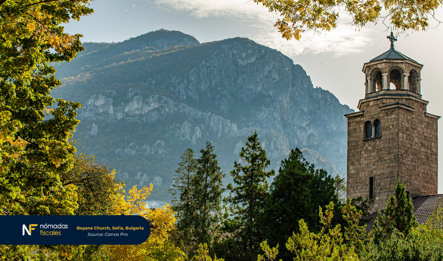 Boyana Church in Sofia, Bulgaria, surrounded by trees with mountains in the background.