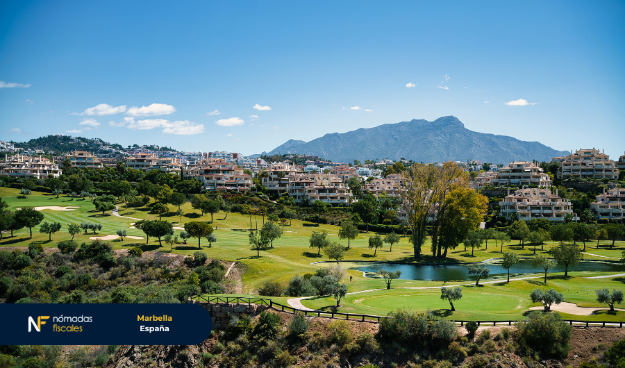 Vista panorámica de un campo de golf en Marbella, España, con edificios residenciales y montañas al fondo